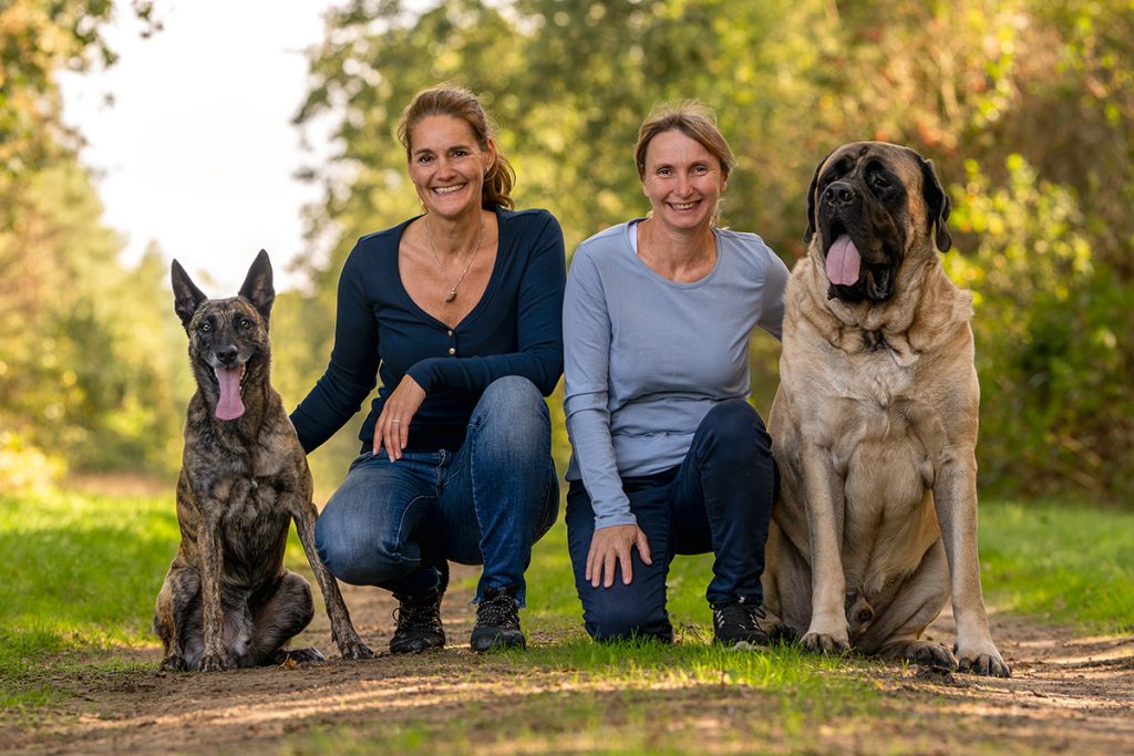 Twee vrouwen poseren met twee honden in een bos