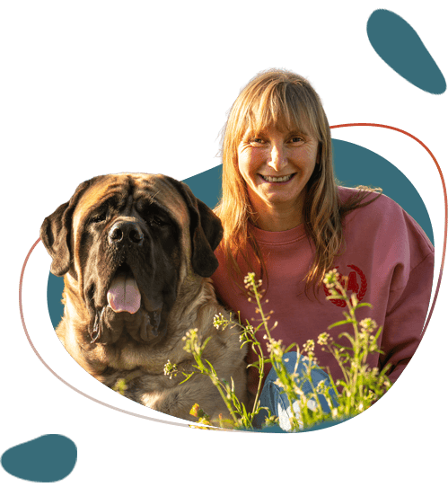 Lachende vrouw met grote mastiff tussen wilde bloemen