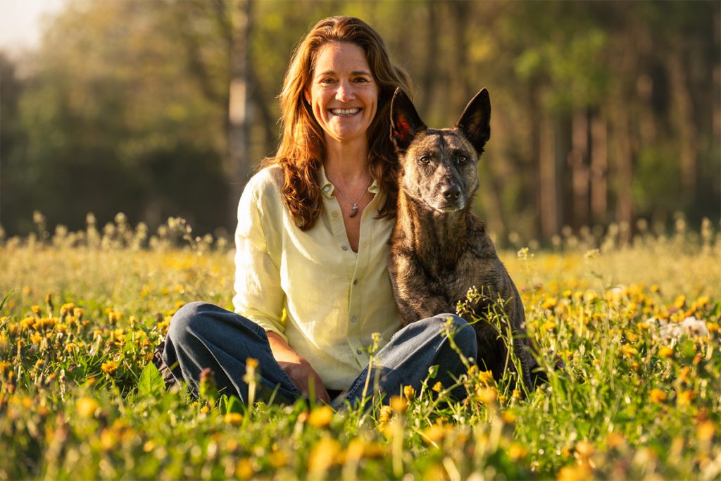 Vrouw zit met hond in zonnige bloemenweide